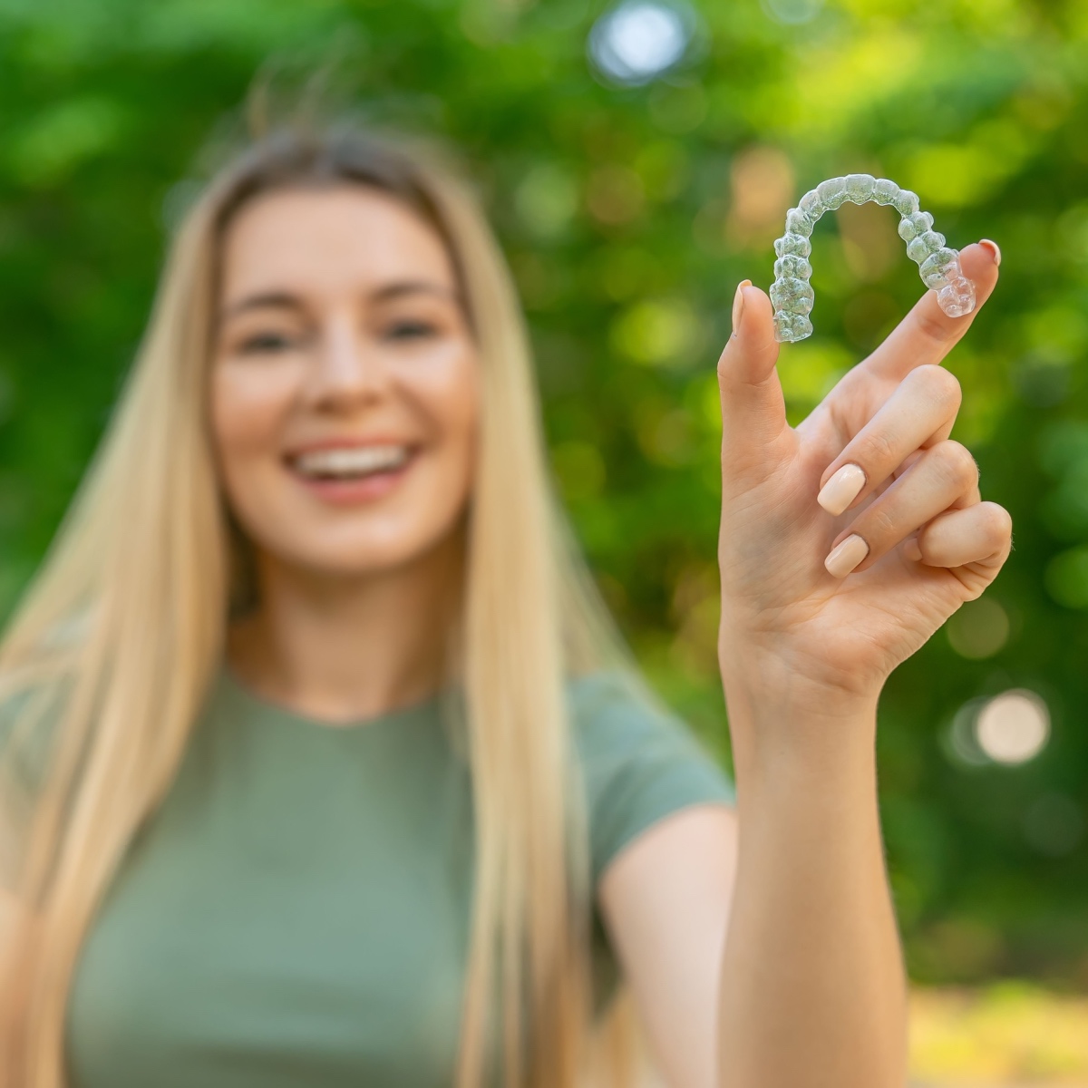 A smiling woman holding Houston Invisalign